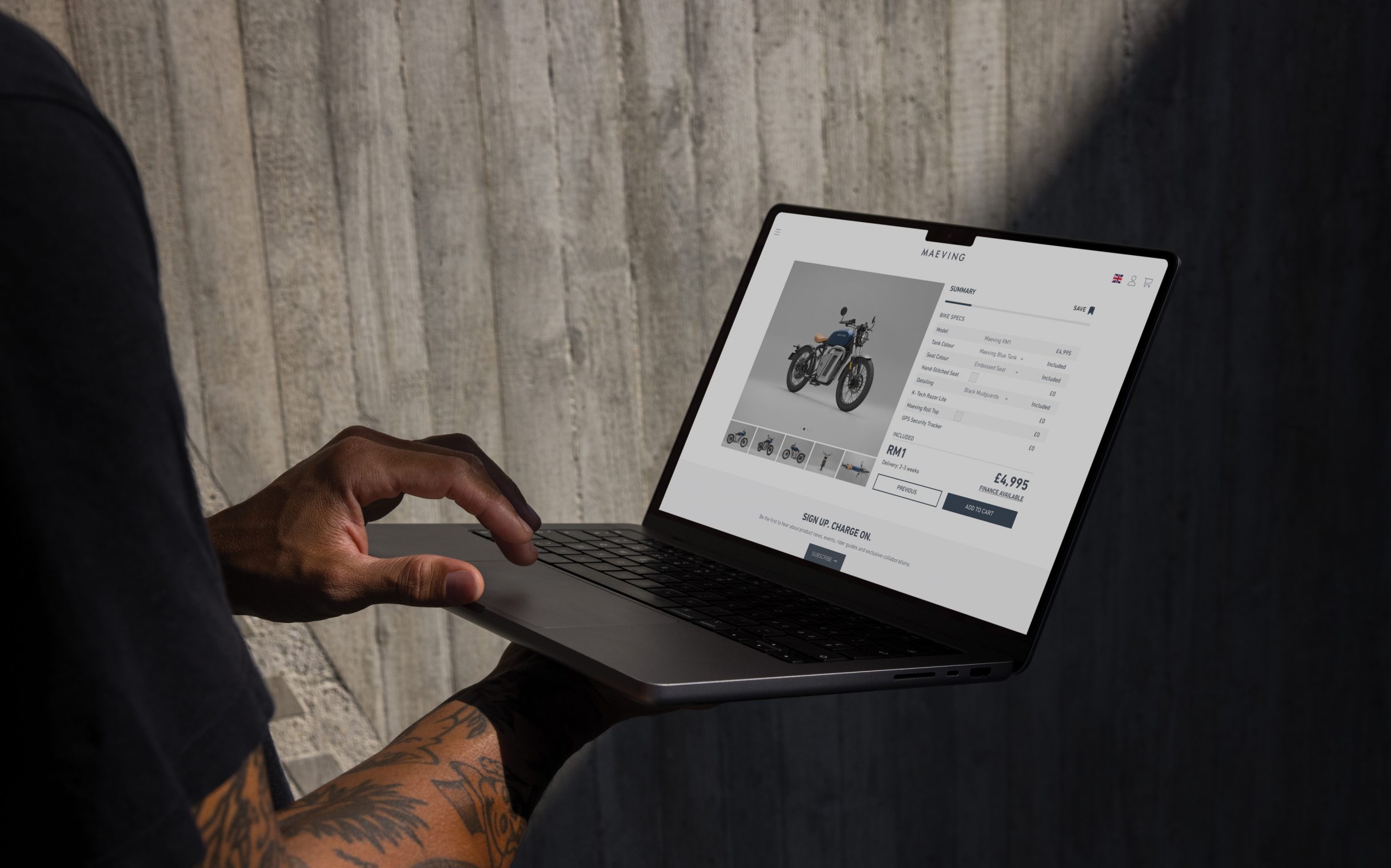 A man using the Maeving website on a laptop being held